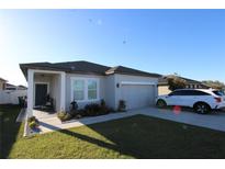 Charming single-Gathering home with well-maintained lawn, covered entry, and attached two-car garage at 881 Orchid Grove Blvd, Davenport, FL 33837