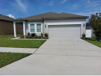 Charming one-story home with a well-manicured lawn and a two car garage at 881 Orchid Grove Blvd, Davenport, FL 33837