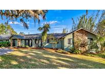 Green house with stone accents, spacious lawn, and mature trees at 647 Ridgewood Dr, Windermere, FL 34786