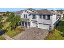 Two-story house with gray exterior, three-car garage, and a paved driveway at 1402 Olympic Club Blvd, Champions Gate, FL 33896