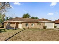 Brick house with a two-car garage and a spacious lawn at 2102 Kingswood Ave, Deltona, FL 32725