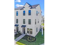 Beautiful three-story townhome with modern design, sleek black windows, and charming walkway leading to the front door at 15142 Grove Lake Dr, Winter Garden, FL 34787