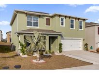 Charming two-story home with green exterior, front yard landscaping, and a two-car garage at 2665 Magnolia Ave, Davenport, FL 33837