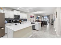 Modern kitchen with white cabinetry, stainless appliances, and an island featuring light countertops and an open concept living area at 4721 Clock Tower Dr # 204, Kissimmee, FL 34746