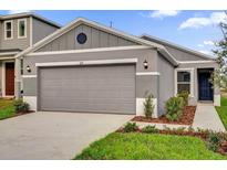 Charming one-story home with a gray exterior, a two-car garage, and landscaped front yard at 219 Ash Way, Auburndale, FL 33823