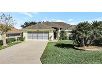 Cute yellow house with gray garage door and nicely landscaped lawn at 5025 St Andrews Arc, Leesburg, FL 34748