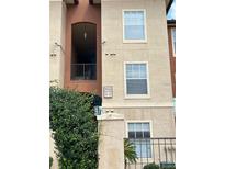Apartment complex exterior featuring neutral tones and gated entrance with green foliage at 5542 Metrowest Blvd # 206, Orlando, FL 32811