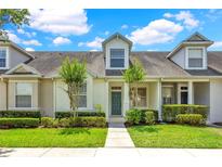 Charming townhome featuring well-maintained landscaping and a welcoming teal front door at 14480 Chinese Elm Dr, Orlando, FL 32828