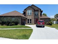 Two-story brick house with a brown roof, attached garage, and a long driveway at 2355 Abalone Blvd, Orlando, FL 32833