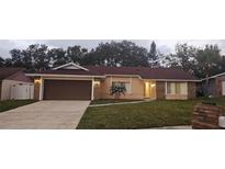 Charming single-story home featuring a brick facade, two-car garage, manicured lawn, and mature landscaping at 1859 Lake Hill Cir, Orlando, FL 32818