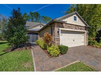 Charming home featuring a manicured lawn, stone accents, and a two-car garage under a clear blue sky at 513 San Sebastian Ct, Davenport, FL 33837
