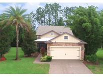 Charming home featuring a stone-accented facade, two-car garage, well-manicured lawn and beautiful tropical landscaping at 513 San Sebastian Ct, Davenport, FL 33837
