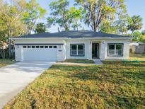 Charming single-story home featuring a large front yard, a two-car garage, and stone accents at 765 W Lansdowne Ave, Orange City, FL 32763