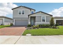 Charming two-story home boasts a well-manicured lawn, brick driveway, and attached garage at 2949 Wild Olive Dr, St Cloud, FL 34772