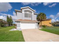 Two-story house with gray siding, white garage door, and palm trees at 3279 Fairfield Dr, Kissimmee, FL 34743