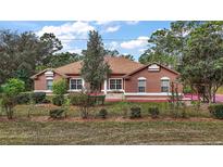 One-story home with brown exterior, landscaped yard, and driveway at 6900 Sw 137Th Court Rd, Ocala, FL 34481