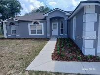 Charming single-story home featuring a well-manicured lawn and inviting facade, complemented by a neatly landscaped pathway at 15613 Greater Groves Blvd, Clermont, FL 34714