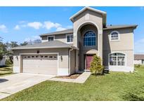 Two-story home boasting an attached garage, well-manicured lawn, and an arched entryway with a large window at 1907 Lakeview Way, Kissimmee, FL 34759