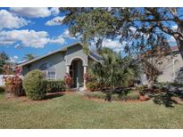 Charming single-story home featuring a well-manicured lawn with mature trees and lush landscaping at 8048 Canyon Lake Cir, Orlando, FL 32835