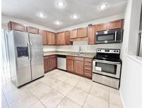 Well-lit kitchen featuring stainless steel appliances and wooden cabinets providing ample storage space at 1918 Conway Rd # 3, Orlando, FL 32812