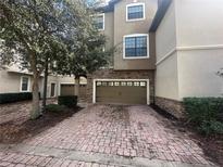 Townhouse exterior featuring a two-car garage with brick paver driveway and stone accents at 1341 Shinnecock Hills Dr, Davenport, FL 33896