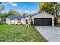 Newly renovated home with a modern exterior, two-car garage, and nicely landscaped lawn at 1704 Ison Ln, Ocoee, FL 34761