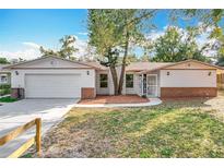 Charming single-story home with a white exterior, attached garage, brick accents, and a well-maintained front yard at 5520 Beggs Rd, Orlando, FL 32810