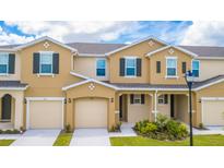 Tan two-story townhome with two-car garage and landscaping at 5149 Adelaide Dr, Kissimmee, FL 34746