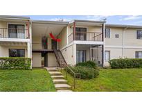 Inviting condo featuring stairs leading to a covered entrance, neutral siding, and lush landscaping around the building's base at 314 Cherokee Ct # H, Altamonte Springs, FL 32701