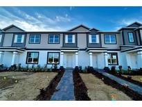 Modern three-story townhome with gray and white siding, and a brick walkway at 592 Pothos St, Apopka, FL 32703