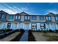 Two-story townhome with gray siding, white accents, and a paved walkway at 600 Pothos St, Apopka, FL 32703