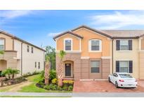 Two-story townhome with orange exterior, landscaping, and a driveway at 8851 Geneve Ct, Kissimmee, FL 34747