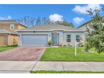 Charming single-story home featuring a brick driveway, a two-car garage, and a well-manicured lawn at 1197 Celery Oaks Ln, Sanford, FL 32771