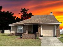 Cute ranch home with a brick facade and attached garage, showcasing a beautiful sunset in the background at 3153 Berridge Ln, Orlando, FL 32812