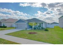 One-story home with gray siding, two-car garage, and landscaped lawn at 229 Talladega Ln, Polk City, FL 33868