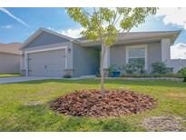 Charming one-story home with a well-manicured lawn and a gray facade at 229 Talladega Ln, Polk City, FL 33868