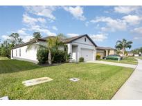 Well-maintained one-story home with green lawn, tidy landscaping, and a two-car garage under a sunny blue sky at 538 Stowers Dr, New Smyrna Beach, FL 32168