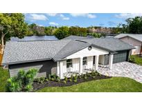 An elevated view of a single-story home with manicured landscaping and gray shingle roof at 2631 Falmouth Rd, Maitland, FL 32751