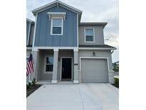 Two-story house with gray and blue siding, two-car garage, and American flag at 3203 Laurent Loop, Davenport, FL 33837