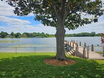Backyard featuring a tree, fenced lawn, dock, and lake with lush greenery along the shoreline at 3651 S Rosalind Ave, Orlando, FL 32806