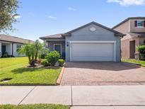 One-story home with gray exterior, two-car garage, and landscaped front yard at 3570 Southern Cross Loop, Kissimmee, FL 34744