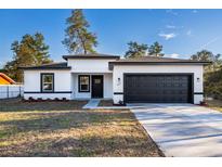 Charming single-story home featuring a black garage door, a white exterior, and a well-manicured front yard at 14962 Sw 39Th Cir, Ocala, FL 34473
