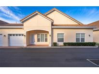 Tan two-story condo building with attached garage and walkway at 2705 Shantiniketan Blvd # H5, Tavares, FL 32778