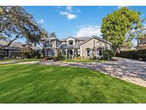 Elegant home with a manicured lawn and a circular driveway at 6025 Lady Bet Dr, Orlando, FL 32819