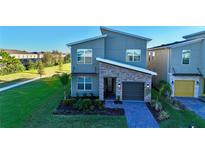 Modern two-story home with gray siding and stone accents at 8900 Takeaway Way, Davenport, FL 33896