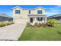 Two-story house with beige siding, a two-car garage, and a landscaped lawn at 5215 Tanzanite Dr, Mount Dora, FL 32757