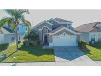 Two-story house with a neutral exterior, two-car garage, and manicured lawn at 8059 King Palm Cir, Kissimmee, FL 34747