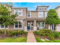 Tan two-story townhome with blue door, brick walkway, and landscaping at 8127 Cadman St, Orlando, FL 32832