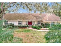 House exterior featuring a red door and well-manicured lawn at 1876 Lake Francis Dr, Apopka, FL 32712