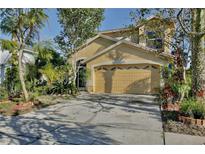 Two story tan house with a large garage surrounded by well manicured landscaping at 2981 Viscount Cir, Kissimmee, FL 34747